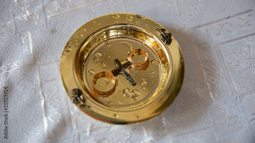The priest holds the wedding rings on a saucer near the bible. Orthodox father bless wedding day in rings for newlyweds. 