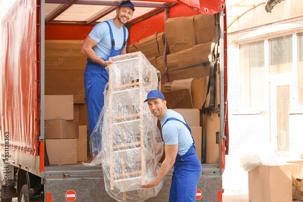 Fototapeta premium Loaders taking furniture from truck outdoors