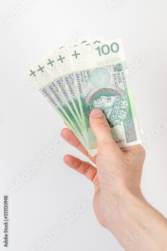 Five 100 PLN banknotes held in right hand.