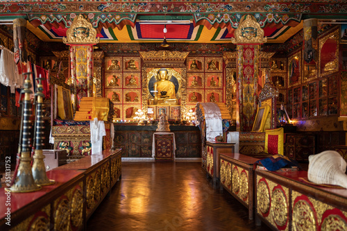 Gompa of one of the Buddhist monasteries, Tibetan Buddhism. A gilded buddha is visible on the altar, in the foreground ritual musical instruments - gyaling and dunkar. © Dymov
