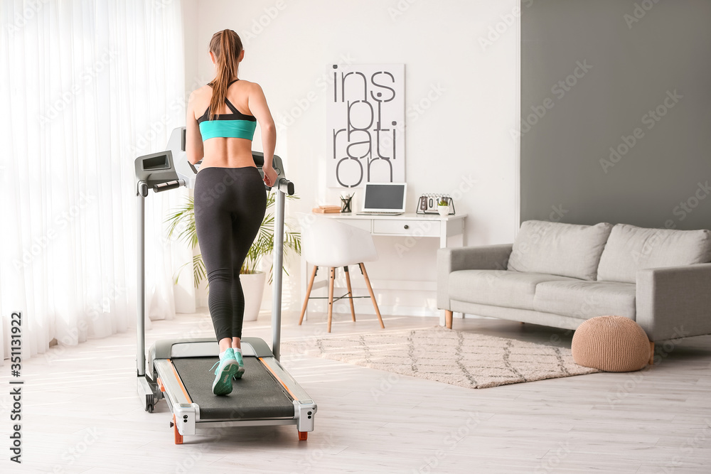 Sporty young woman training on treadmill at home Sporty young woman training on treadmill at home