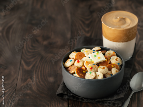 Mini pancakes cereal and dalgona coffee on brown wooden background, copy space. Trendy food and drink - tiny panckakes served sprinkles and whipped instant coffee with milk or korean dalgona coffee photo