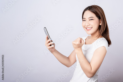 Asian pretty woman glad to something in her mobile phone with copy space. Telling, shopping promotion, announcement and successfull concept.