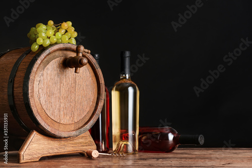 Fototapeta Naklejka Na Ścianę i Meble -  Wooden barrel and bottles of wine on dark background