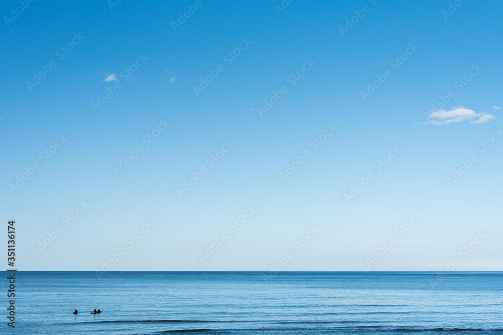blue sky and surfers in the sea