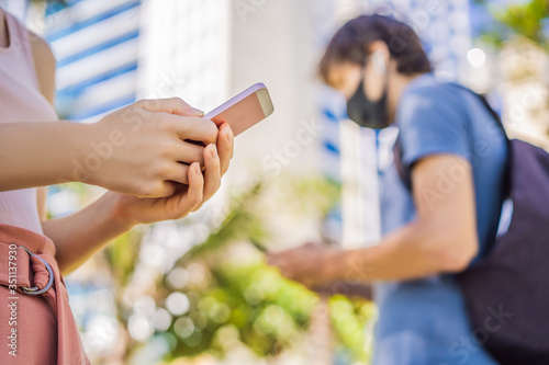contact tracing app COVID-19 Pandemic Coronavirus Mobile Application - people Wearing Face Mask Using Smart Phone App in City Street to Aid Contact Tracing in Response to the 2019-20 Coronavirus