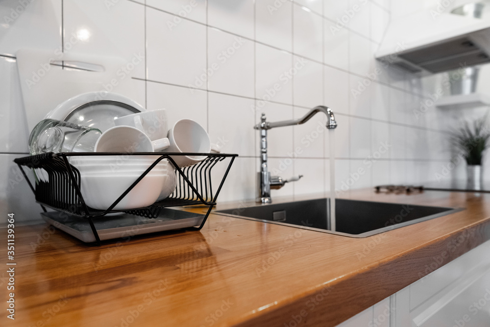 Dish Rack Holds Many Dishes And Cups Against Wooden Countertop White Wall  Tiles Sink And Faucet Budget And Lightweight Antimicrobial Dish Drainer  With Drain Board At Modern Scandinavian Kitchen Stock Photo 