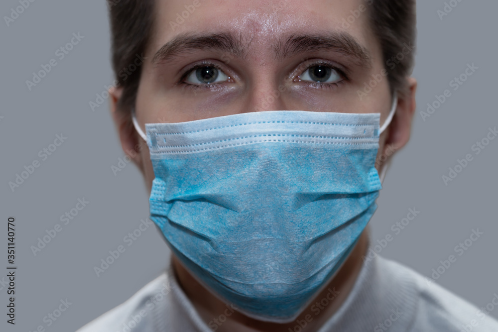 Young man in a medical mask smiles, portrait