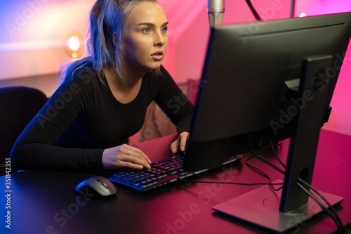 Focused Professional E-sport Gamer Girl with Headset Playing Online Video Game on PC