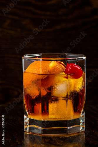 old fashion cocktail in a glass of rox on a black background photo