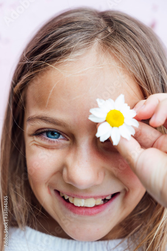 Portrait of little girl with blue eyes and a flower