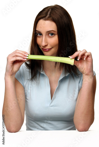 A woman placing her thumb into a long green vegetable