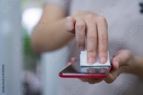 Female hands use alcohol to wipe clean the phone, protect the virus