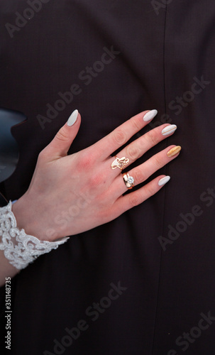 Bride's hand with a ring gold on the groom's shoulder. © TsarPro