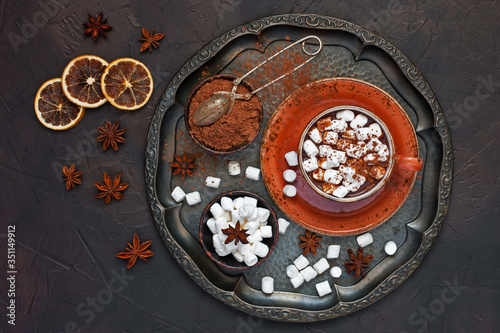 Hot chocolate drink with spices on dark background, flat lay