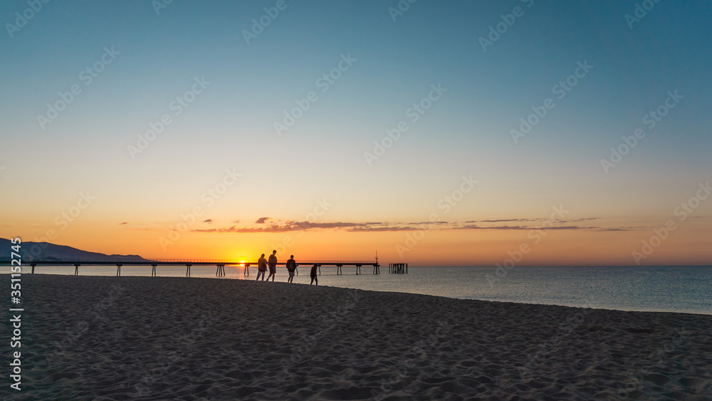 group of friends walking on the beach at dawn