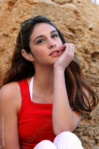 A girl in red sleeveless top resting her chin on her palm