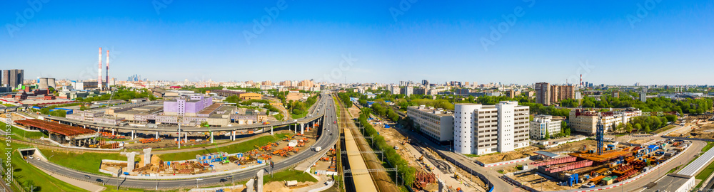Power plant pipes and cooling towers in Moscow from above, automobile traffic and and construction of a new car overpass and interchange in the Moscow industrial zone near the automobile ring highway