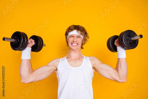 Close-up portrait of his he nice attractive sportive guy sportsman doing work out lifting heavy barbell self developing isolated over bright vivid shine vibrant yellow color background photo