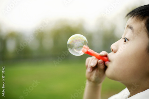 Boy blowing out soap bubble