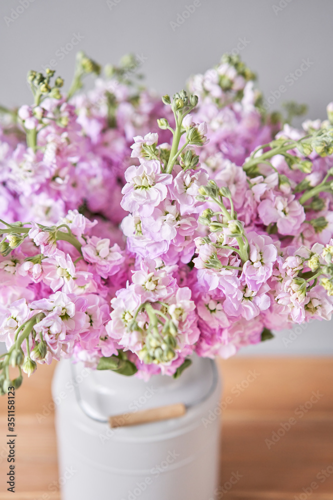 Fototapeta premium Bouquet of Beautiful lilac mattiola. Spring flowers in vase on wooden table. Flowers delivery.