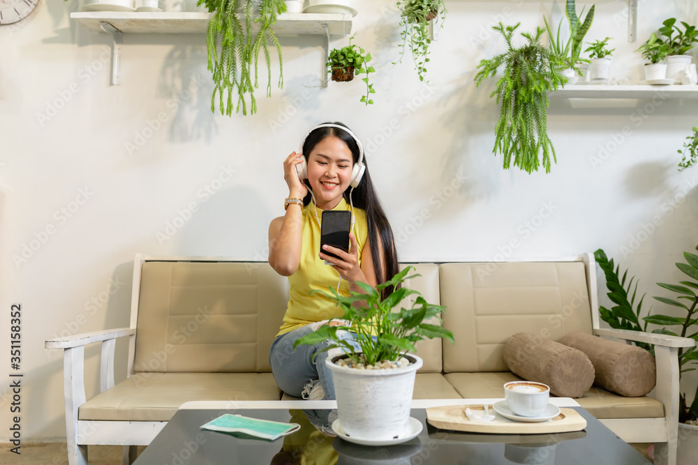 Asian smiling girl student wear wireless headphone study online with skype teacher in a coffee shop, woman learn language listen lecture watch at phone sit in cafe, distant education, New normal Asian smiling girl student wear wireless headphone study online with skype teacher in a coffee shop, woman learn language listen lecture watch at phone sit in cafe, distant education, New normal
