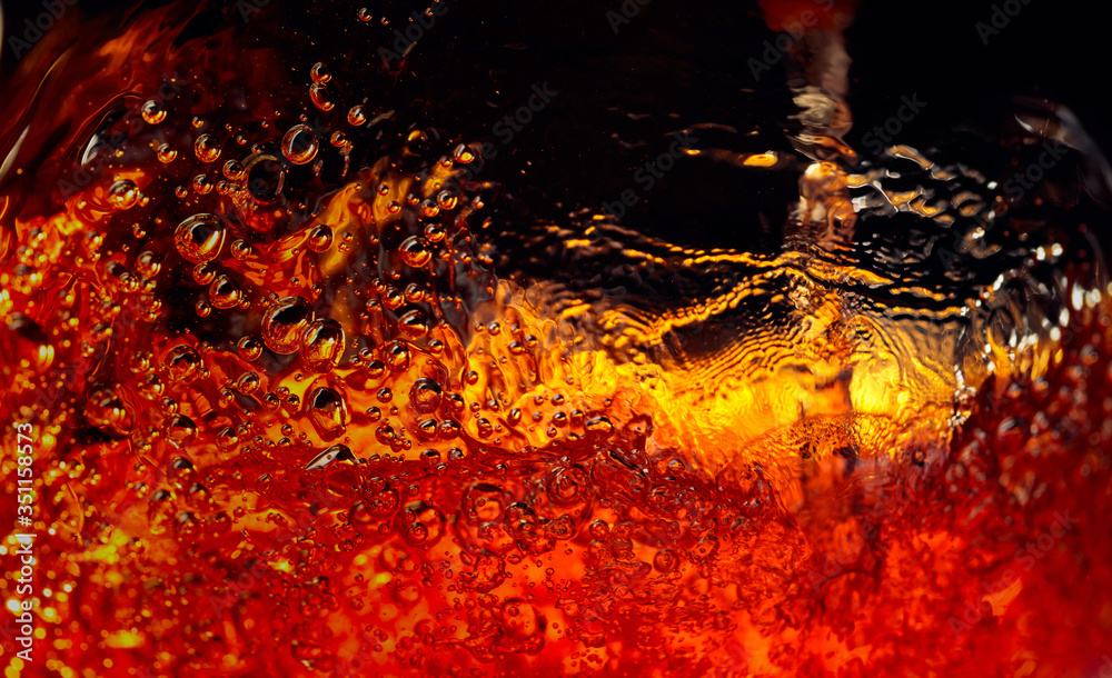 Carbonated drink in glass, abstract splashing.