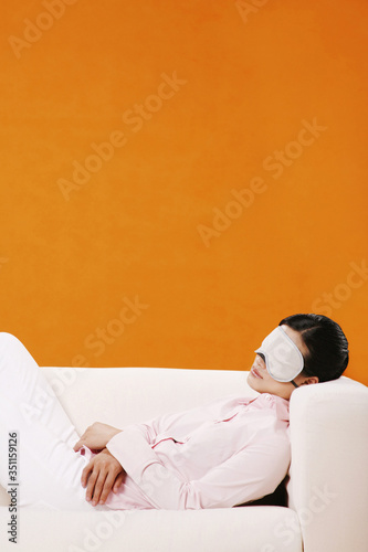 Woman lying on couch, wearing sleep mask