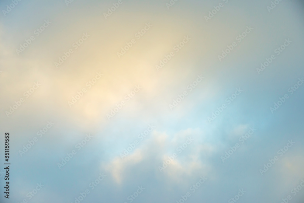 White clouds in a misty sky at a yellow foggy sunrise in an early spring morning