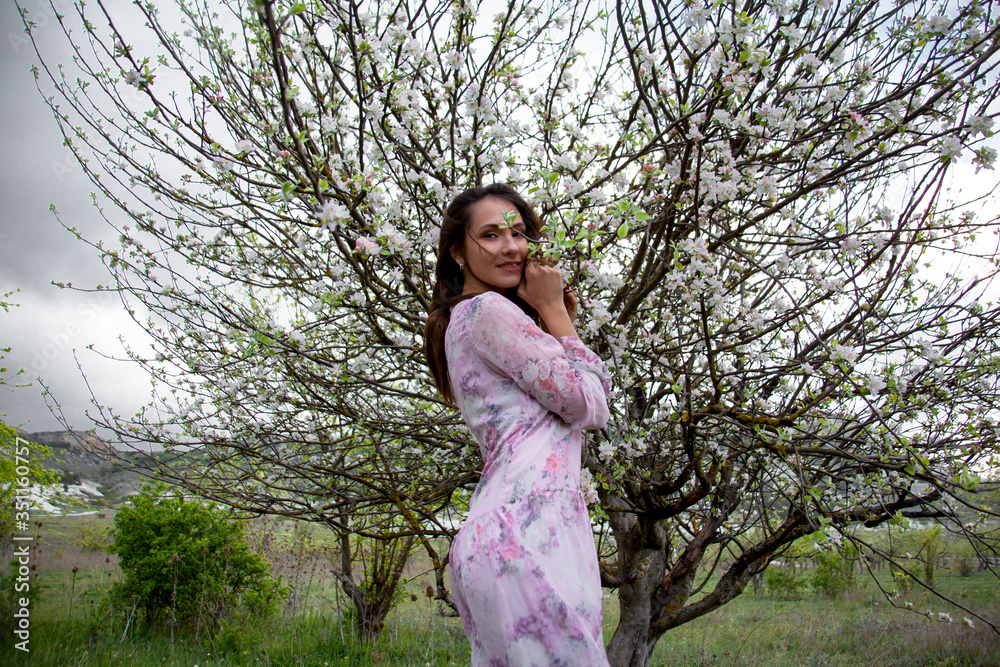 Pretty woman dressed pink dress, walking in the countryside garden of flower trees in the nature Pretty woman dressed pink dress, walking in the countryside garden of flower trees in the nature