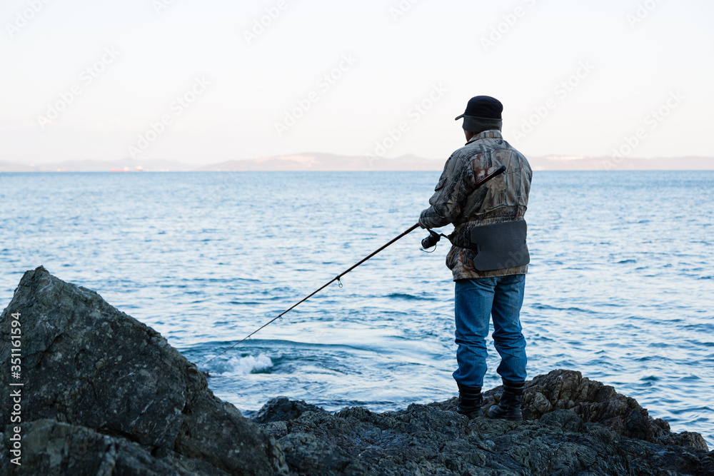 Fisherman on evening fishing on the rocks
