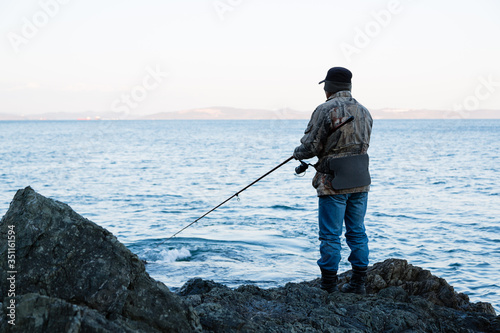 Fisherman on evening fishing on the rocks