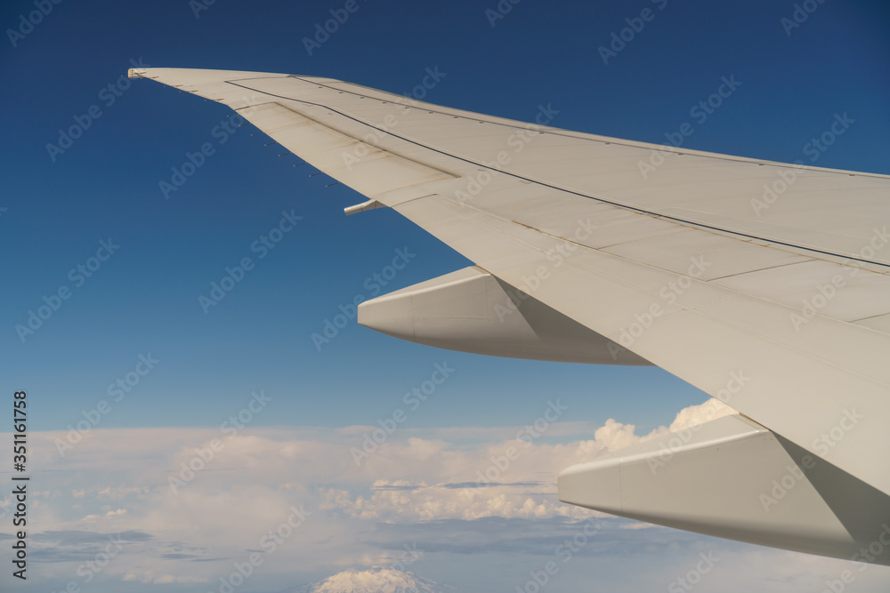 Flying and traveling, view from airplane window on the wing on a cloudy day. Wing of an airplane flying above the morning clouds.