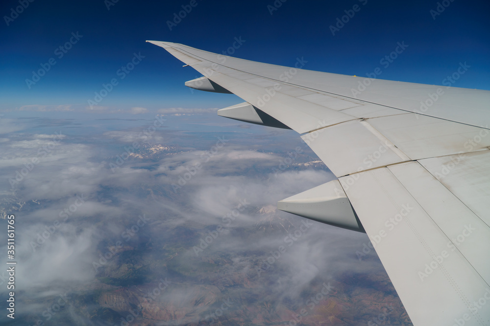 Flying and traveling, view from airplane window on the wing on a cloudy day. Wing of an airplane flying above the morning clouds. Flying and traveling, view from airplane window on the wing on a cloudy day. Wing of an airplane flying above the morning clouds.