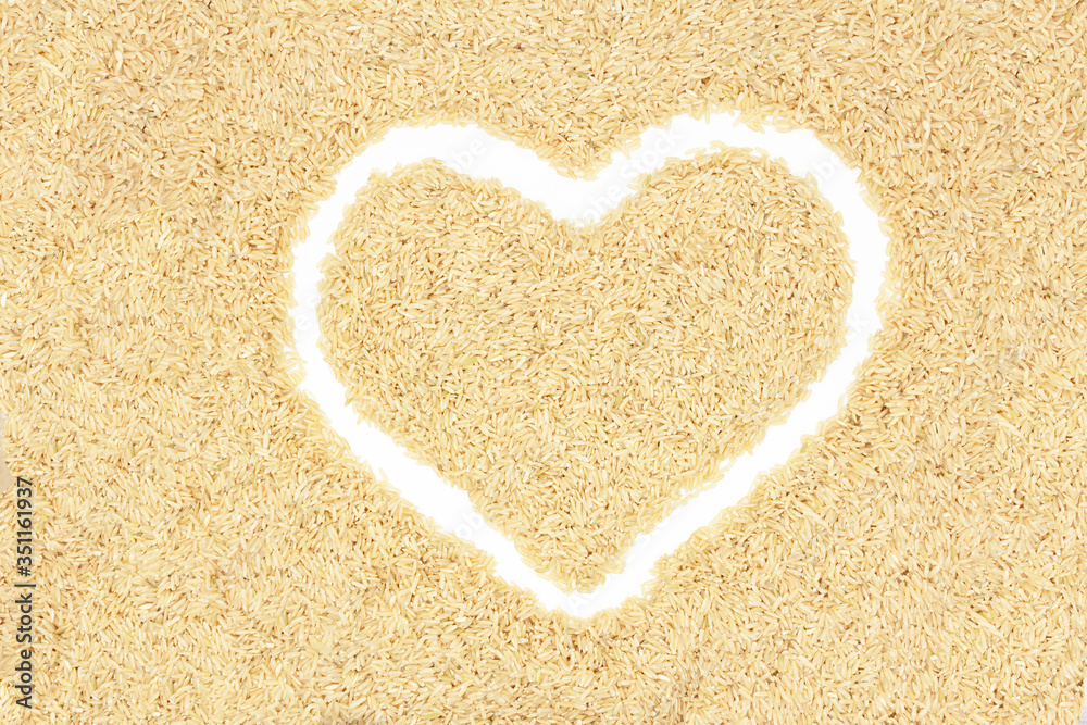 Texture of brown long rice in an even layer. Laid out the outline of a white heart. Texture of brown long rice in an even layer. Laid out the outline of a white heart.