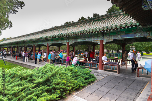 People resting and playing card games in the Temple of Heaven site in Beijing, China on a summer day