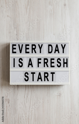 'Every day is a fresh start' words on a lightbox on a white wooden surface, top view. Overhead, from above, flat lay.