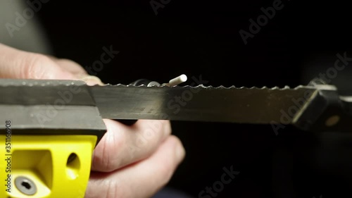 Professional serrated knife blade sharpening with a rotary tool by a manual labour. Specks of metal flying away. Macro shot