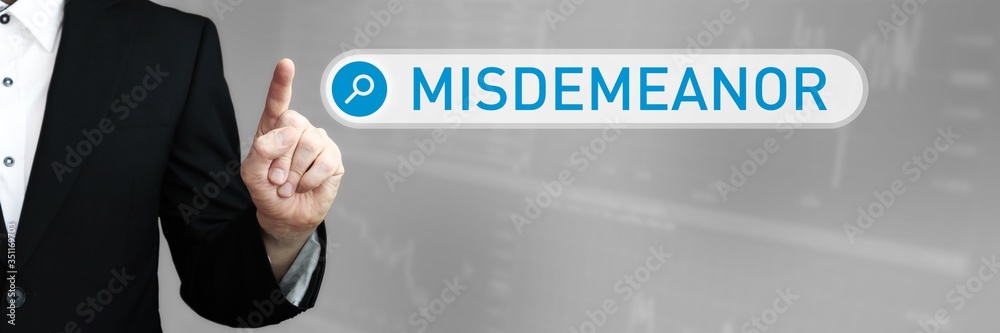 Misdemeanor. Businessman (Man) in a suit pointing with his finger to a search box. The word is in focus. Blue Background. Business, Finance, Statistics, Analysis, Economy Misdemeanor. Businessman (Man) in a suit pointing with his finger to a search box. The word is in focus. Blue Background. Business, Finance, Statistics, Analysis, Economy