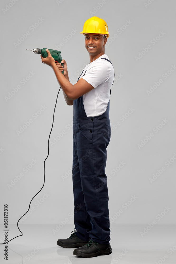 profession, construction and building - happy smiling indian worker or builder in helmet with electric drill or perforator over grey background profession, construction and building - happy smiling indian worker or builder in helmet with electric drill or perforator over grey background