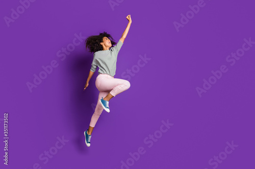 Full length photo of crazy funny afro american girl jump hold hand try catch parasol wear casual style pink outfit isolated over purple color background