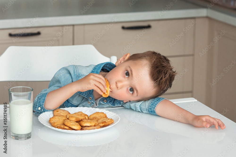 Cute little boy eats cookies with milk