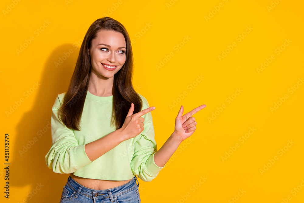 Photo of attractive lady good mood direct fingers side empty space showing novelty product wear green cropped sweatshirt jeans isolated vivid bright yellow color background Photo of attractive lady good mood direct fingers side empty space showing novelty product wear green cropped sweatshirt jeans isolated vivid bright yellow color background