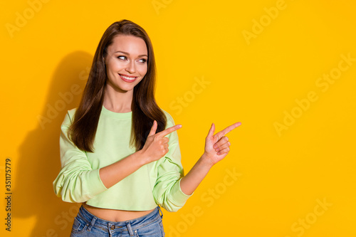 Photo of attractive lady good mood direct fingers side empty space showing novelty product wear green cropped sweatshirt jeans isolated vivid bright yellow color background
