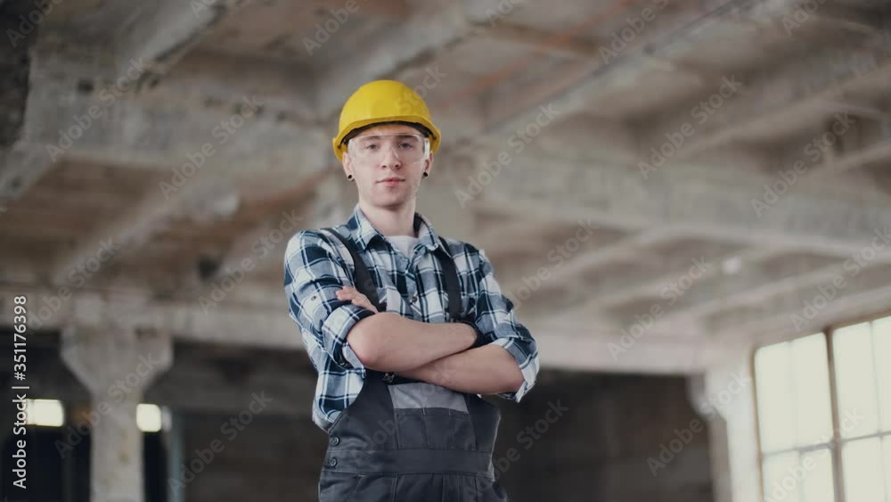Portrait of a builder in a helmet and overalls, great design for any purpose. Work safety. Indoors. Construction site. Building industry concept. Portrait of a builder in a helmet and overalls, great design for any purpose. Work safety. Indoors. Construction site. Building industry concept.