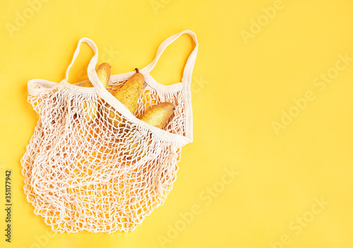 Cotton net bag with pears. Eco friendly concept. yellow background. Top view