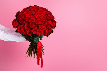 Photo of cropped man arms hold big one hundred red bright roses bunch giving secret admirer delivery service worker valentine day romance concept isolated pink color background
