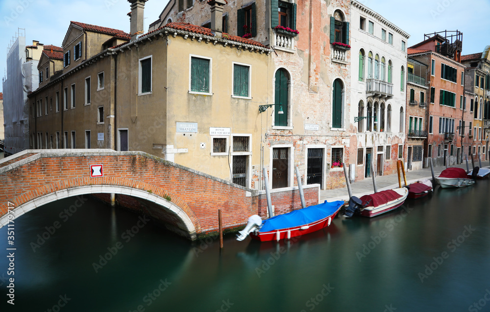 Navigable canal in Venice with boats photographed with the long