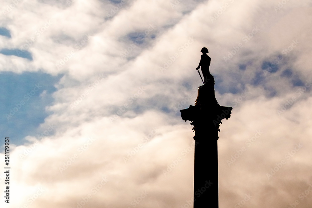 Nelson's column silhouette in Trafalgar Square, London against a cloudy sky at dusk