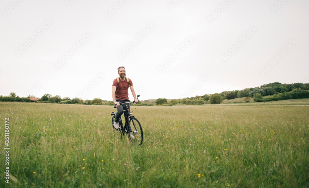 Bearded man riding bicycle in nature, copy space Bearded man riding bicycle in nature, copy space